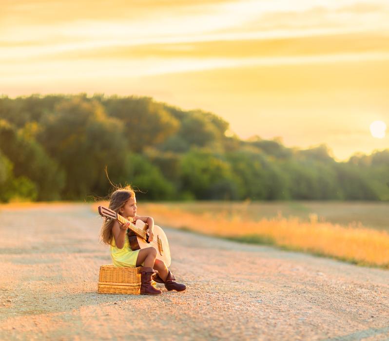 girl with guitar on the road in the countryside