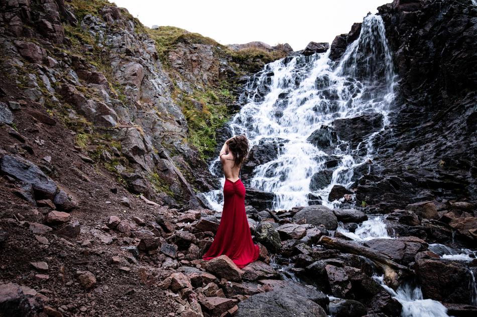 Woman in red waterfall near the beautiful waterfall with rocks