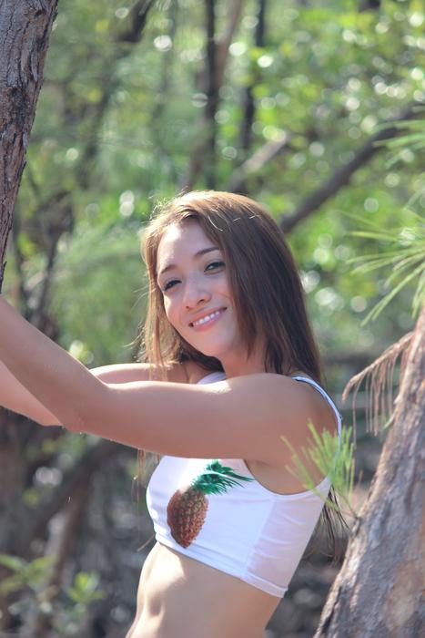 Portrait of the smiling girl in summer view, posing among the green trees