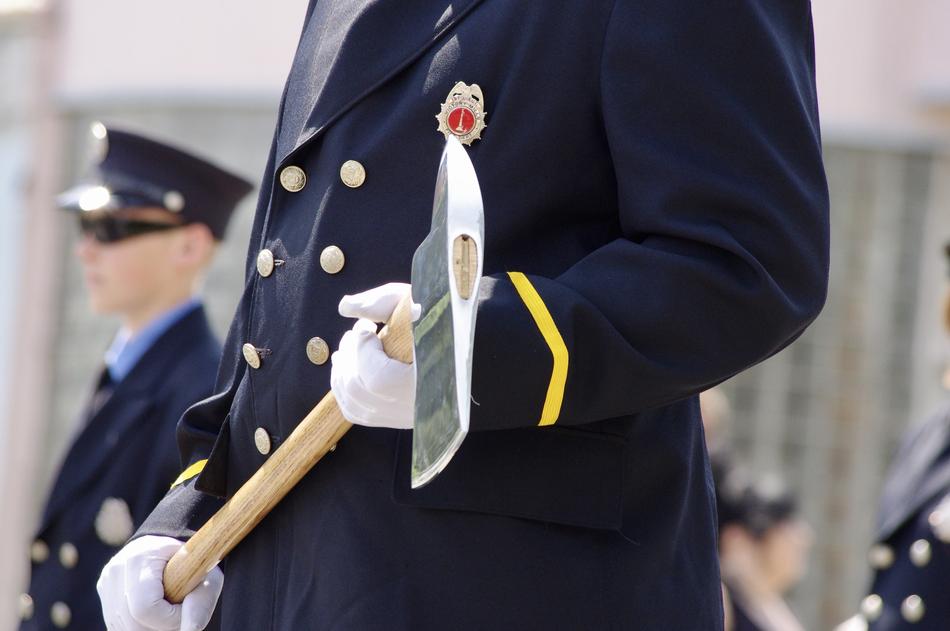 Man in military uniform, holding axe in hands, among the other men