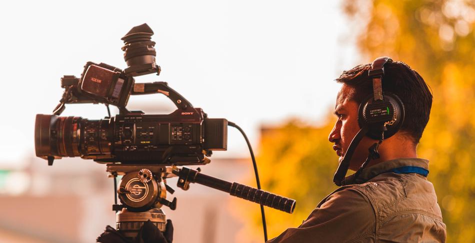 Profile portrait of the working cameraman with headphones, at blurred background