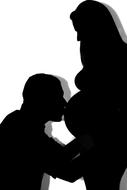 silhouette of a man kissing a pregnant woman