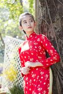 Asian girl in beautiful red and white dress, posing among the green plants