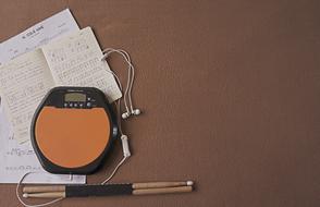 music player, drumsticks and music notebooks on the table