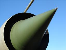 Close-up of the green part of the jet fighter, at blue sky on background