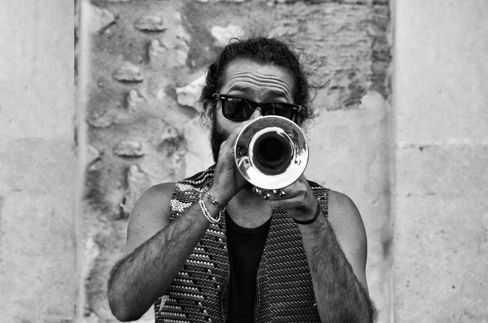 Black and white portrait of the man with trumpet, near the building