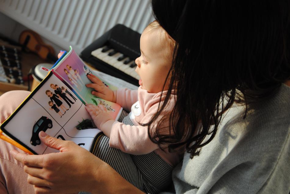 Mother reading colorful booklet with the images, with the cute child