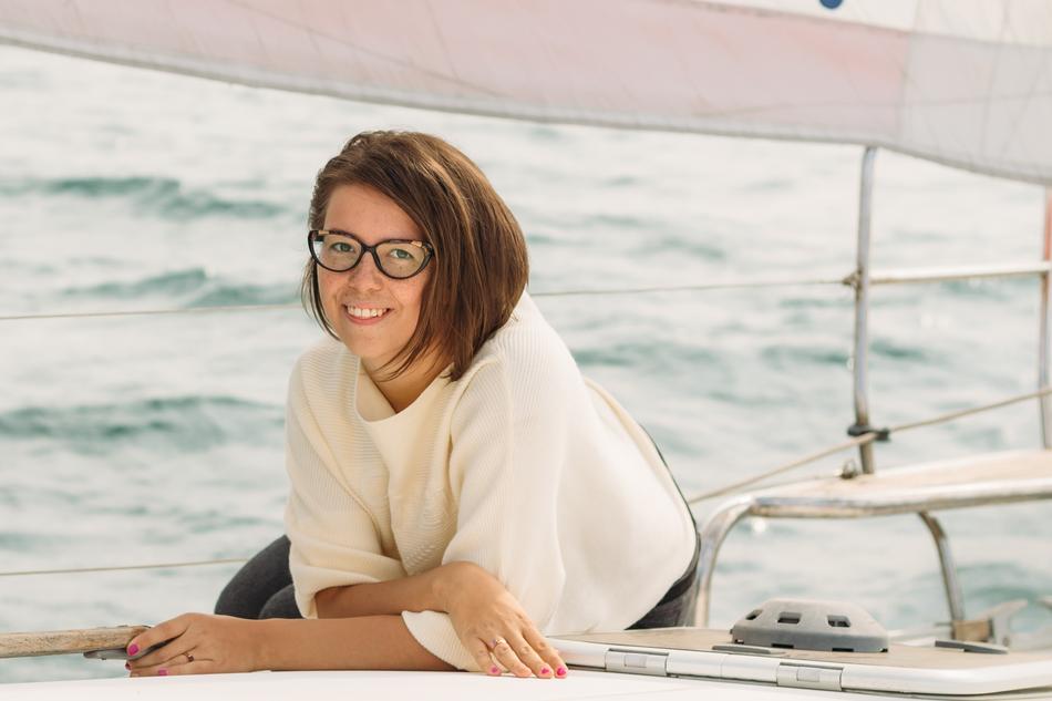 Smiling girl with glasses, posing on a yacht, among the water with ripple