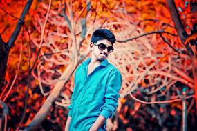 guy in sunglasses on a background of red trees in the park
