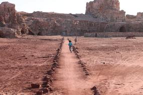 Boy running on the path, at background with the rocks