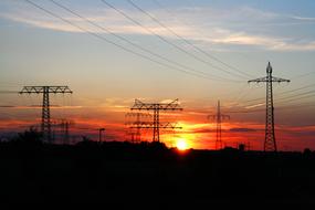 Silhouettes of the electricity towers, at colorful and beautiful sunset on horizon, among the clouds, in the Elbe Valley, Germany