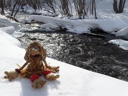 papuan doll on the snowy bank of the river in winter