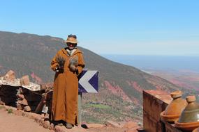 Man in hat, posing on the beautiful and colorful landscape with the mountains, with plants