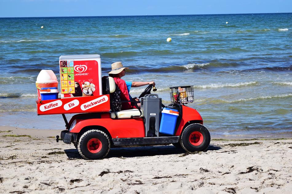 Dealer driving colorful cart on the sandy beach of the Baltic Sea