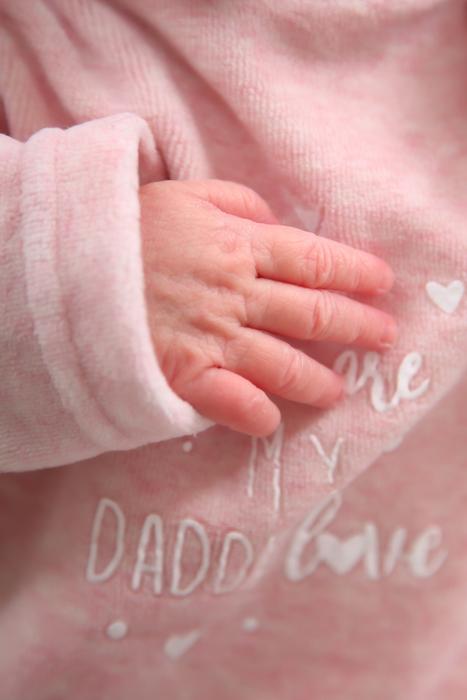 Newborn Baby in pink clothing with Hand on chest