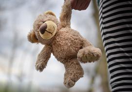 child holding a teddy bear by the paw