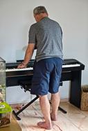 barefoot senior man plays piano for fun