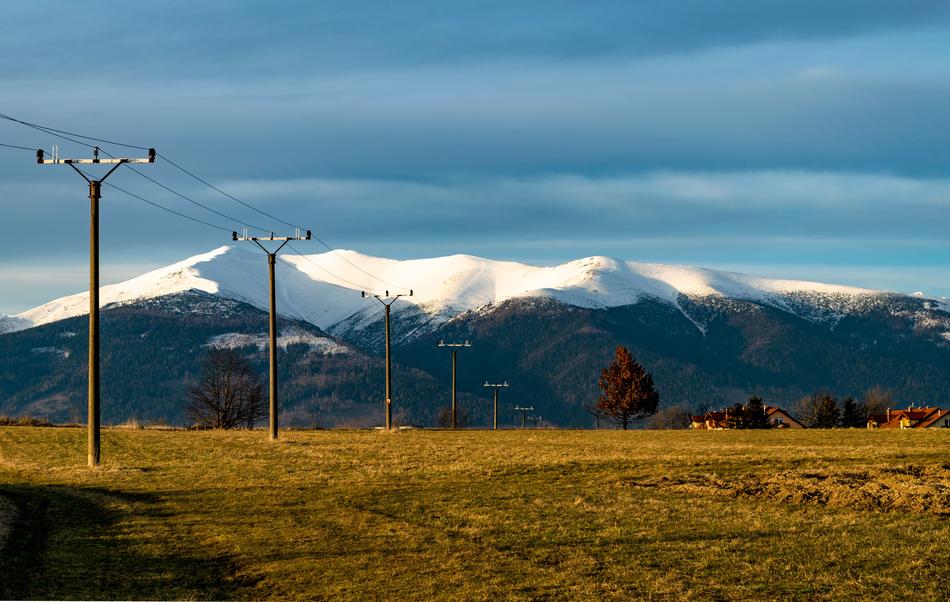 pillars with electricity on the field against the background of mountains