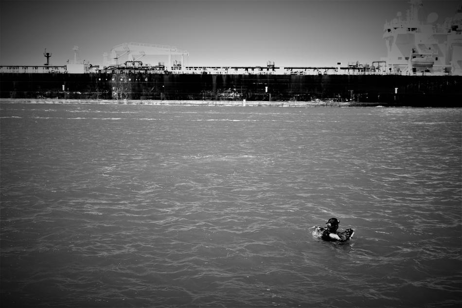 Black and white photo of the river with people, near the coast