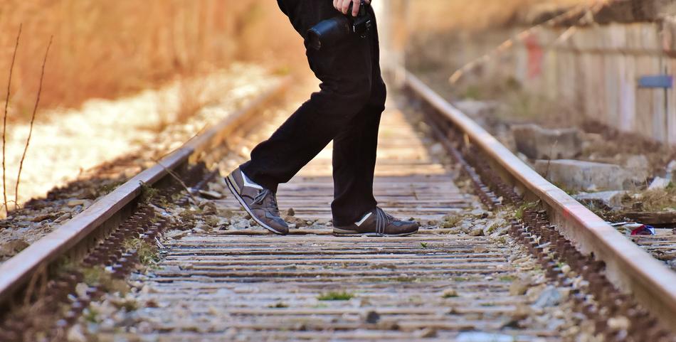 Person walking on the old railroad track among the colorful plants