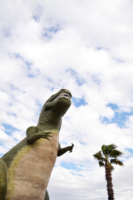 dinosaur sculpture by a tree