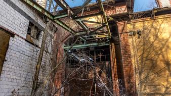 Old, rusty, industrial construction, among the plants, under the blue sky