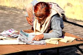 senior asian Woman reading newspaper on pavement