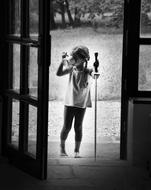 black and white, the girl drinks from a mug in front of the entrance