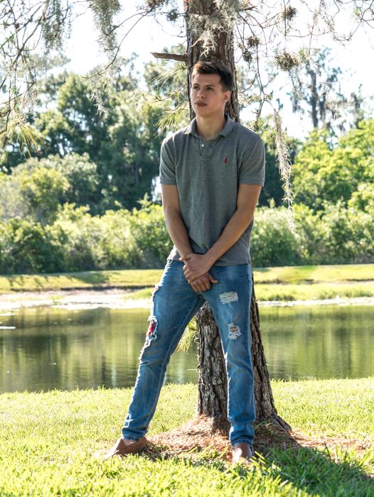 handsome Young Man leaning on tree at summer
