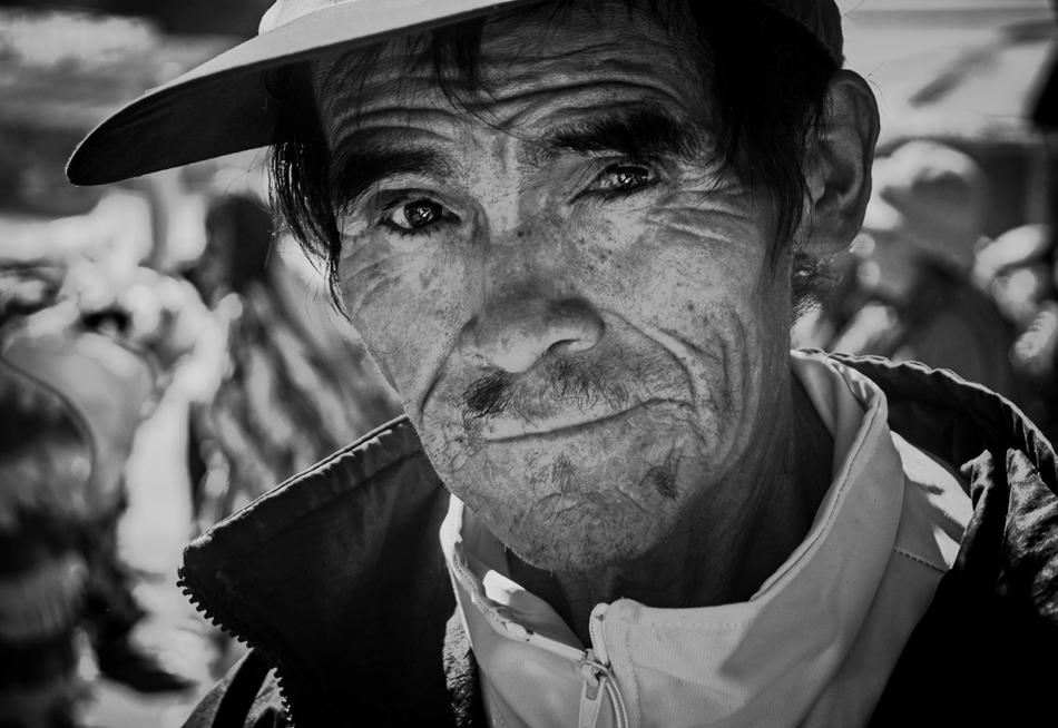 Black and white portrait of the old, Peruvian man in cap, at blurred background