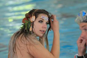 Portrait of the girl with colorful mermaid decorations, near the man and water