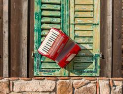 Old red accordion on wooden shutters