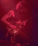 man with tattoo on hand plays guitar in red light