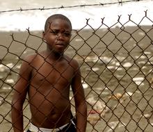 Shirtless guy standing behind the fence in Haiti