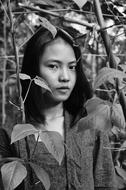 Black and white portrait of the Asian woman, among the beautiful plants and leaves