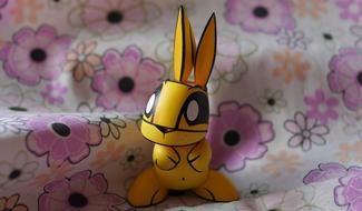 Beautiful and cute, yellow and black toy of the rabbit, on the surface with colorful flowers