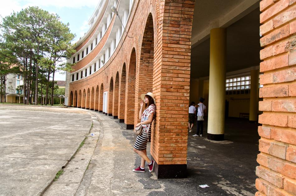 Student girl standing near the brick building with arches, and other people