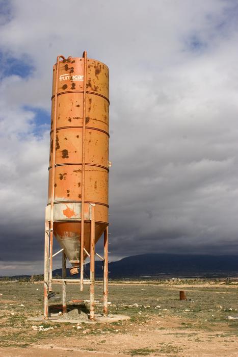 Hopper tower, among the beautiful and colorful field, near the mountains, under the blue sky with clouds