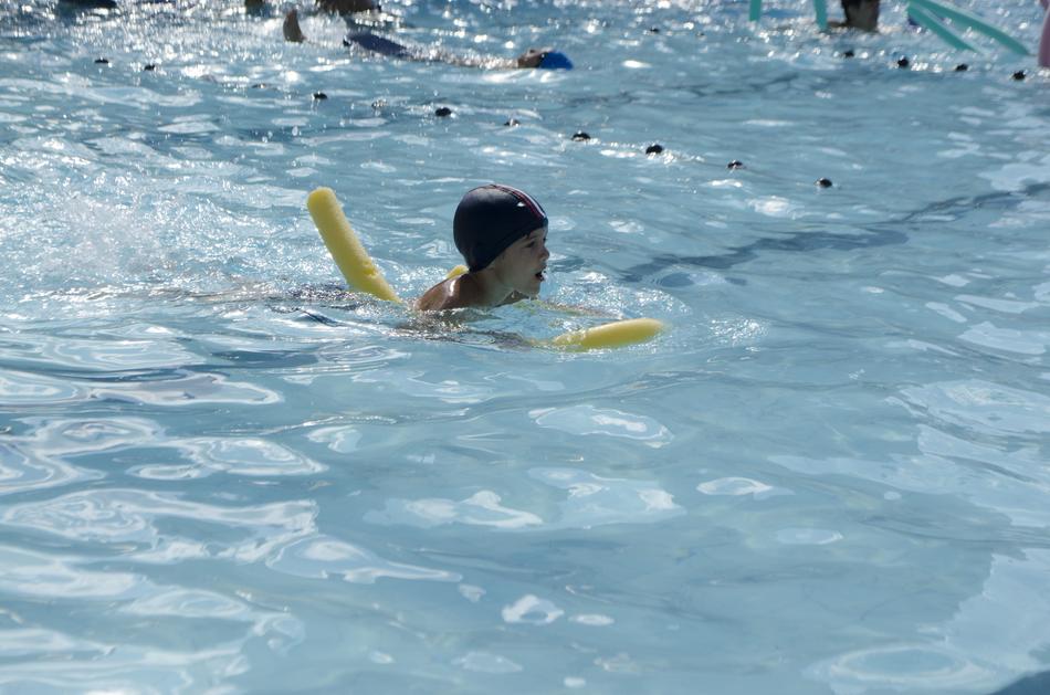 Child swimming in the pool with yellow toy