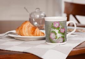 beautiful mug with a picture of flowers and a croissant