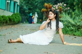 a girl in a white dress on the ground