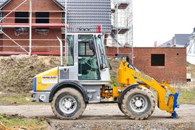 Yellow and blue machine on the landscape, near the building