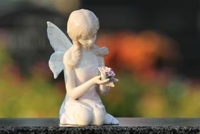 winged Girl with roses in hands figurine at blur background