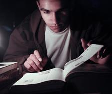 Portrait of a man, reading the book, in light, among the darkness