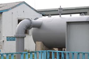 Close-up of the grey industrial pipe near the building, outdoors