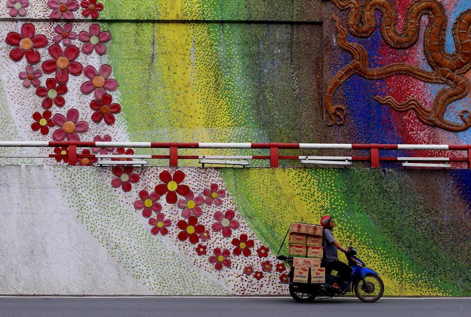 delivery man on a motorcycle against the background of a wall with graffiti in Hanoi, Vietnam