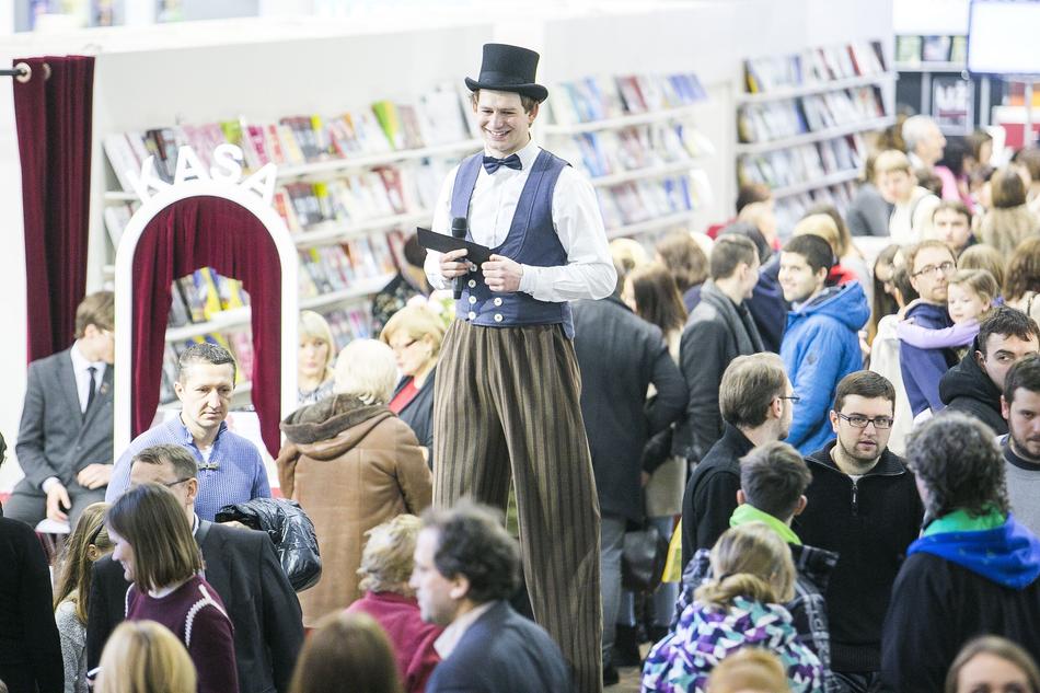 Man in hat, on acrobatic stilts, among the other people at the festival