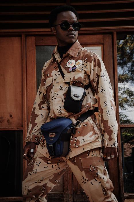 Man with sunglasses, and in military clothing with equipment, near the building