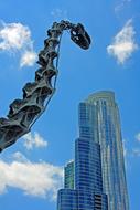 Iron sculpture of a dinosaur against a background of houses