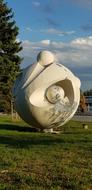 White atom sculpture, among the colorful plants, under the blue sky with clouds